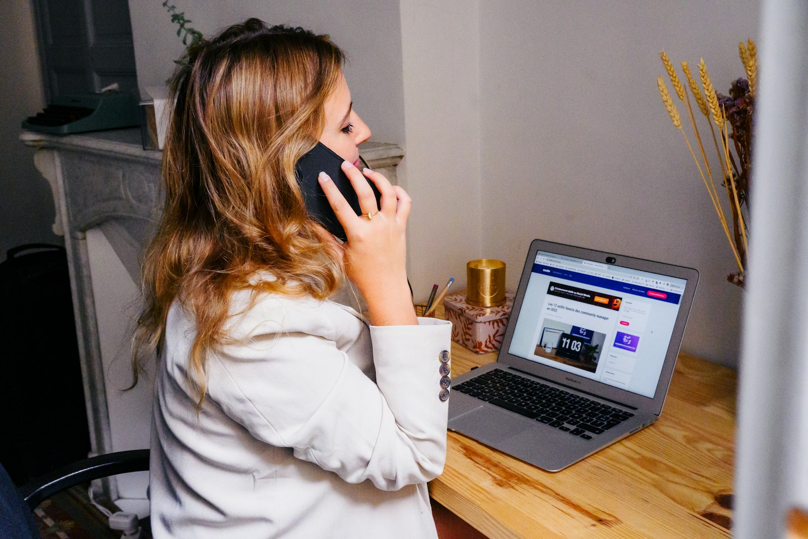 A person on a phone call at an office desk with a computer screen open in front of them