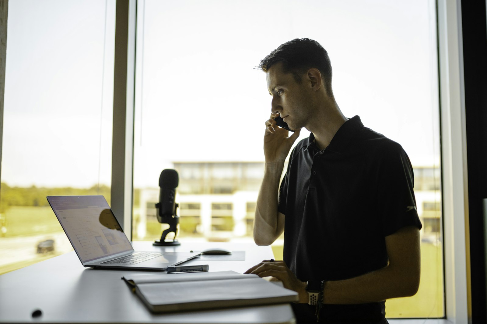 A person making a phone call at an office desk with an open notebook in front of them